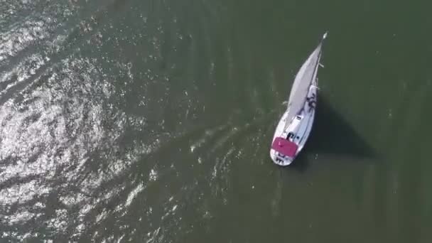 Luftaufnahme eines einsamen Seglers auf tiefblauem Wasser. ein einsames Boot auf dem Fluss. Luftaufnahme grüner Inseln und Wolken am sonnigen Sommermorgen — Stockvideo