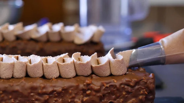 Baka en tårta. Klämma grädden på moset. Läckra smaskiga krämen pressas på kakan — Stockfoto