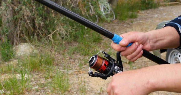 Fishermans fishing rod with inertia-free coil in summer on shore of lake close up — Stock Photo, Image