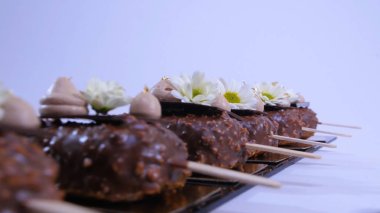 Dondurma, çikolata ile kaplı. Çikolatalı dondurma bir sopa. Çikolatalı dondurma çiçeklerle süslenmiş bir sopa