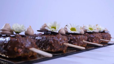 Çiçekler ve krem dondurma portre üzerinde. Çikolatalı dondurma bir sopa. Çikolatalı dondurma çiçeklerle süslenmiş bir sopa