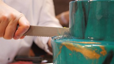 Pasta şefi pasta uzun bir bıçak ile kesmek. Turkuaz bir pasta kesti. Pasta şefi pasta kesme