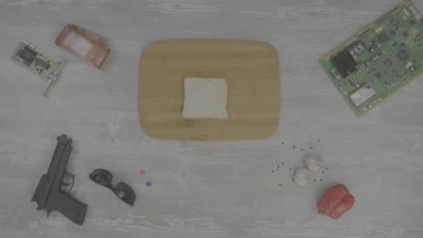 Homem coloca o pão na tábua de corte sobre a mesa são: arma, óculos, chip e pimenta, a abstração para instagram — Vídeo de Stock