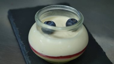 Ev yapımı yoğurt bir cam kavanoza yaban mersini ile. El koyarak çilekli yoğurt, yakın çekim