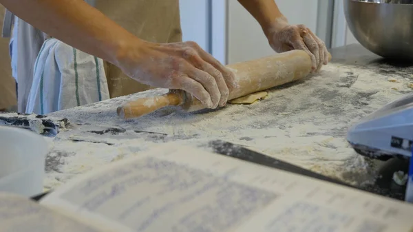 Detalj av kvinnans hand rulla ut en deg med en brödkavel när du gör hemlagad pasta. Kvinnans händer rullande degen — Stockfoto