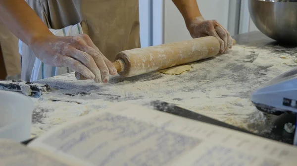 Detalj av kvinnans hand rulla ut en deg med en brödkavel när du gör hemlagad pasta. Kvinnans händer rullande degen — Stockfoto