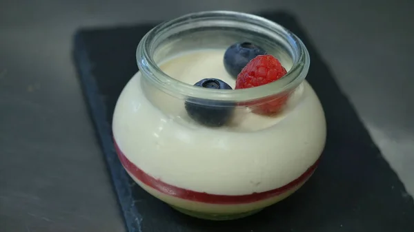Domácí jogurt s borůvkami ve skleněné nádobce. Ruční zavedení jahoda v jogurtu, zblízka — Stock fotografie