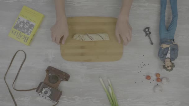 Kochen gefüllter Pfannkuchen. Auf dem Tisch liegt: ein Buch, eine alte Kamera, Zwiebeln, Knoblauch und Spielzeug im Stil von instaram — Stockvideo
