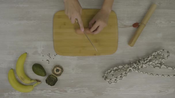 Mans mão na tábua de madeira com uma faca cortando uma salsicha. Na mesa há muitas tesouras, uma faca, uma abstração para o instagram. — Vídeo de Stock