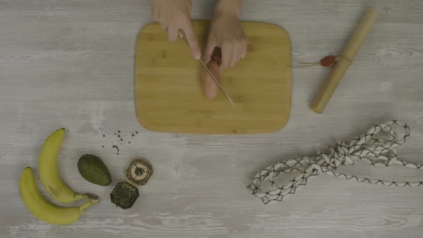 Mans mano sulla tavola di legno con un coltello che taglia una salsiccia. Sul tavolo ci sono molte forbici, un coltello, un'astrazione per instagram — Video Stock