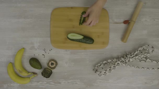 Mano de hombre en la tabla de madera con un cuchillo que corta un pepino. En la mesa hay un montón de tijeras, un cuchillo, una abstracción para instagram — Vídeo de stock