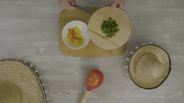 Sätter mat i skålen med en kniv. På bordet är två mexikanska hattar, maracas, abstraktion för instagram — Stockvideo