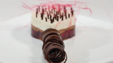 Bir plaka üzerinde üç kat kremalı pasta. Kremalı pasta çikolata kırıntıları ve çikolata saman ile dekore edilmiş üç kat ile