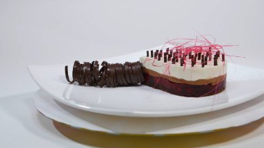 Bir plaka üzerinde üç kat kremalı pasta. Kremalı pasta çikolata kırıntıları ve çikolata saman ile dekore edilmiş üç kat ile