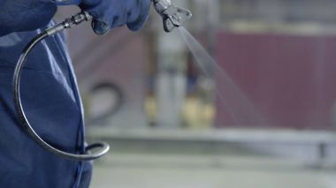 Endüstriyel boyutu sprey boyama ve kaplama sanayi için kullanılan silah tutan el kol. Erkek el boya sprey, closeup tutarak