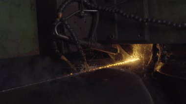 Kaynakçı ile kişisel koruyucu ekipman tam olduğunu gerçekleştirmek otomatik kaynak sistemi kullanarak karanlık bölgede boru kaynak. Kaynak her yere yayılan kıvılcım. Otomat kaynak boru üretimi