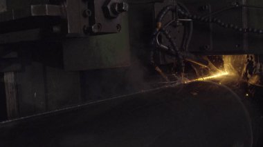 Kaynakçı ile kişisel koruyucu ekipman tam olduğunu gerçekleştirmek otomatik kaynak sistemi kullanarak karanlık bölgede boru kaynak. Kaynak her yere yayılan kıvılcım. Otomat kaynak boru üretimi