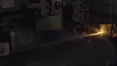Kaynakçı ile kişisel koruyucu ekipman tam olduğunu gerçekleştirmek otomatik kaynak sistemi kullanarak karanlık bölgede boru kaynak. Kaynak her yere yayılan kıvılcım. Otomat kaynak boru üretimi