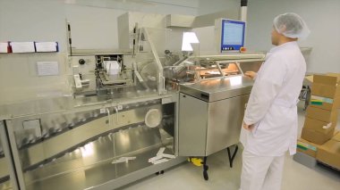 İlaç endüstrisi. Hap ilaç fabrikasında paketleme kalitesini teftiş erkek fabrika işçisi. Otomatik bant ambalaj ve dolum ilaçların oluşturmak için. fabrikada kontrol
