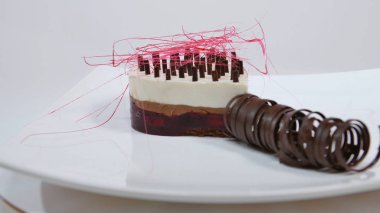 Bir plaka üzerinde üç kat kremalı pasta. Kremalı pasta çikolata kırıntıları ve çikolata saman ile dekore edilmiş üç kat ile