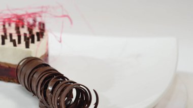 Bir plaka üzerinde üç kat kremalı pasta. Kremalı pasta çikolata kırıntıları ve çikolata saman ile dekore edilmiş üç kat ile