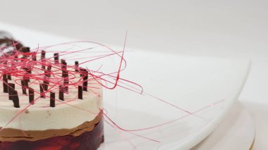 Bir plaka üzerinde üç kat kremalı pasta. Kremalı pasta çikolata kırıntıları ve çikolata saman ile dekore edilmiş üç kat ile