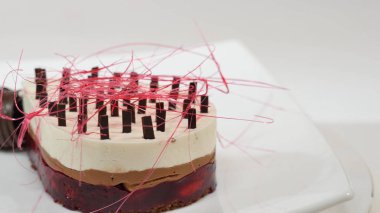 Bir plaka üzerinde üç kat kremalı pasta. Kremalı pasta çikolata kırıntıları ve çikolata saman ile dekore edilmiş üç kat ile