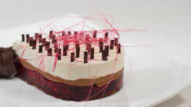 Bir plaka üzerinde üç kat kremalı pasta. Kremalı pasta çikolata kırıntıları ve çikolata saman ile dekore edilmiş üç kat ile