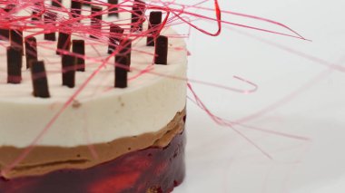 Bir plaka üzerinde üç kat kremalı pasta. Kremalı pasta çikolata kırıntıları ve çikolata saman ile dekore edilmiş üç kat ile