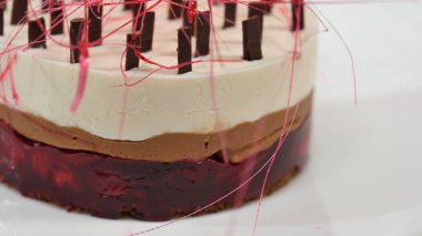 Bir plaka üzerinde üç kat kremalı pasta. Kremalı pasta çikolata kırıntıları ve çikolata saman ile dekore edilmiş üç kat ile