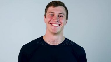 Mavi t-shirt genç İspanyol adamla portresi, ayakta ve gülüyor beyaz arka plan üzerinde - kahkaha kavramı izole. Adam giyen güçlü mavi t-shirt ayakta ve zor gülüyor