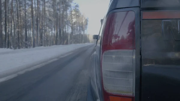 Primer plano del faro en carreteras nevadas. El coche monta en una carretera cubierta de nieve —  Fotos de Stock