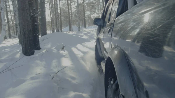 Paseos en coche en un camino forestal de invierno. Un coche en un camino cubierto de nieve entre los árboles —  Fotos de Stock