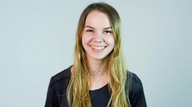 Kamera beyaz arka plan üzerinde seyir gülümseyen genç güzel sevimli neşeli kız. Ağır çekim