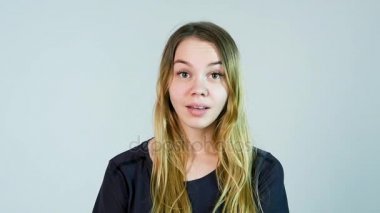 Şok kadın. Yüzünü elleriyle dokunuyor ve kamera beyaz arka plan karşı dururken bakan genç kadın. Ağır çekim