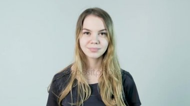 Genç, güzel, neşeli, gülümseyen kız beyaz arka planda kameraya bakıyor.