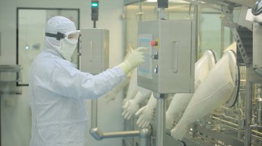 İlaç üretim çalışan bir işçi iş başında. Robotik Kol ilaç fabrikasında paketleme hattı, ampul kaldırma. İlaç endüstrisi. Ampul paketleme makinesi