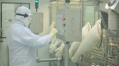 İlaç üretim çalışan bir işçi iş başında. Robotik Kol ilaç fabrikasında paketleme hattı, ampul kaldırma. İlaç endüstrisi. Ampul paketleme makinesi