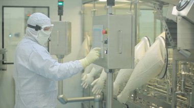 İlaç üretim çalışan bir işçi iş başında. Robotik Kol ilaç fabrikasında paketleme hattı, ampul kaldırma. İlaç endüstrisi. Ampul paketleme makinesi