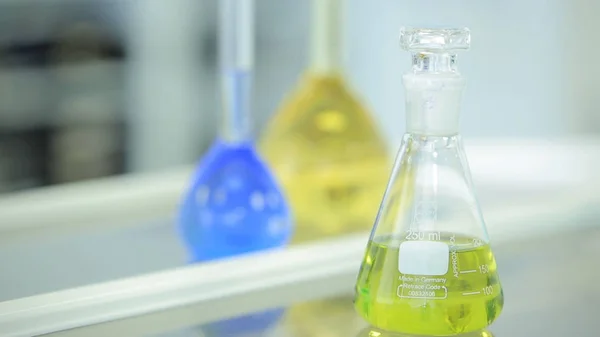 白い背景の上の緑と青の液体と化学のフラスコ。カラフルな化学試薬を試験管。研究室のガラス。化学実験室。選択的 cocus。ボケ味。科学者と医療 — ストック写真