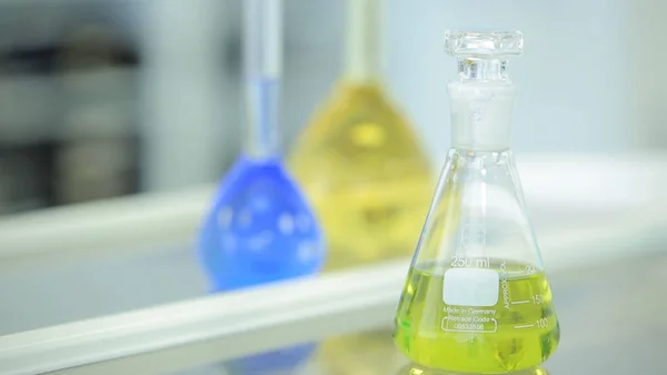 Flacons chimiques avec liquide vert et bleu sur fond blanc. Tubes à essai avec réactif chimique coloré. Verrerie de laboratoire. Laboratoire chimique. Cocus sélectif. Bokeh. scientifique et médical — Photo