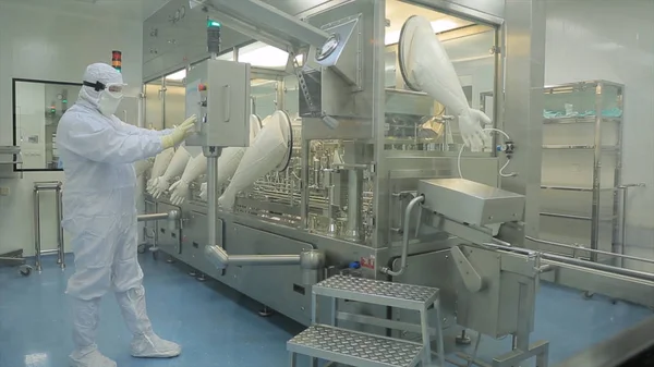 İlaç üretim çalışan bir işçi iş başında. Robotik Kol ilaç fabrikasında paketleme hattı, ampul kaldırma. İlaç endüstrisi. Ampul paketleme makinesi
