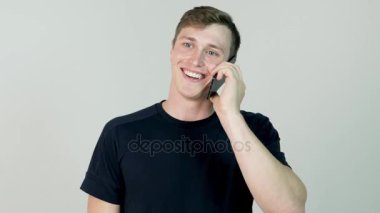 Beyaz arka plan üzerinde cep telefonu konuşma gülümseyen latin yetişkin adam portresi. Işık duvara telefonda konuşan genç casual adam