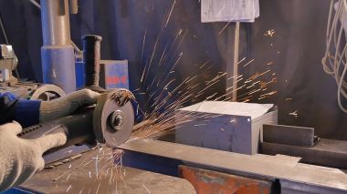 Zanaatkar atölyede disk öğütücüyle metal testeresi kesiyor. Metal testereyle kesiliyor. Metal testeresi üreten bir işçi. Ağır çekimde endüstri