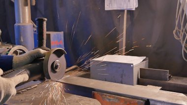 Zanaatkar atölyede disk öğütücüyle metal testeresi kesiyor. Metal testereyle kesiliyor. Metal testeresi üreten bir işçi. Ağır çekimde endüstri