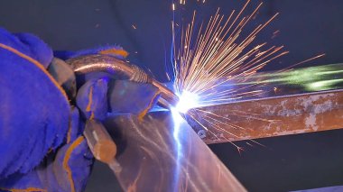 Metal kaynak kıvılcım ve duman ile. İşçi kaynak metal koruyucu maske ile. Kaynakçı metal parçalar katılır. Bir yarı otomatik kaynak kullanan işlem. Kaynak çelik. Fabrikada sanayi işçisi