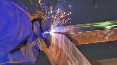 Metal kaynak kıvılcım ve duman ile. İşçi kaynak metal koruyucu maske ile. Kaynakçı metal parçalar katılır. Bir yarı otomatik kaynak kullanan işlem. Kaynak çelik. Fabrikada sanayi işçisi