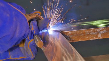 Metal kaynak kıvılcım ve duman ile. İşçi kaynak metal koruyucu maske ile. Kaynakçı metal parçalar katılır. Bir yarı otomatik kaynak kullanan işlem. Kaynak çelik. Fabrikada sanayi işçisi