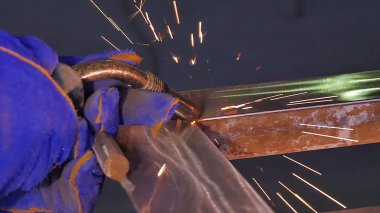 Metal kaynak kıvılcım ve duman ile. İşçi kaynak metal koruyucu maske ile. Kaynakçı metal parçalar katılır. Bir yarı otomatik kaynak kullanan işlem. Kaynak çelik. Fabrikada sanayi işçisi
