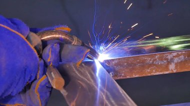 Metal kaynak kıvılcım ve duman ile. İşçi kaynak metal koruyucu maske ile. Kaynakçı metal parçalar katılır. Bir yarı otomatik kaynak kullanan işlem. Kaynak çelik. Fabrikada sanayi işçisi